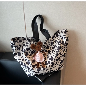 Chic cow print canvas tote bag with black strap handles and a cute plush mouse charm