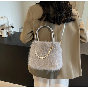 Gray faux fur handbag with pearl chain detail shown on shoulder with brown blazer