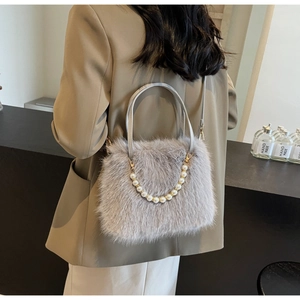 Detail of grey plush faux fur crossbody bag with pearl strap worn by a model