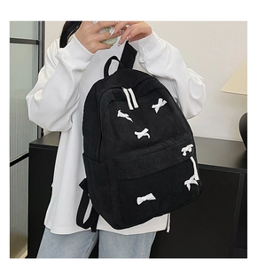 Texture détaillée du sac à dos en velours côtelé noir avec des nœuds blancs décoratifs