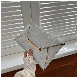 Détail d'une pochette argentée à paillettes avec texture scintillante et bordure dorée