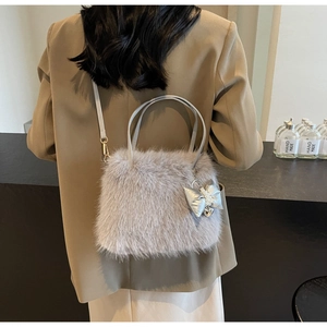 Detailed view of gray faux fur handbag with silver bow charm and pearl strap accents