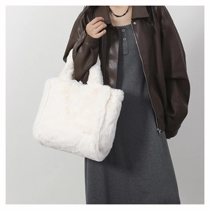 Sac fourre-tout en peluche blanche porté par un mannequin en veste de cuir marron