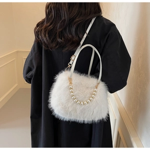 Detail of white faux fur crossbody bag with pearl chain strap on black coat