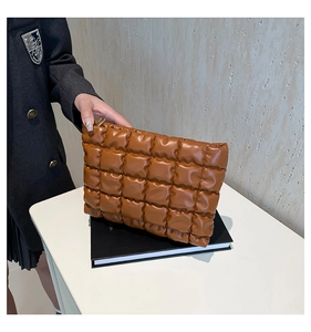 Détail de la pochette matelassée en cuir PU marron foncé avec texture rembourrée et zip