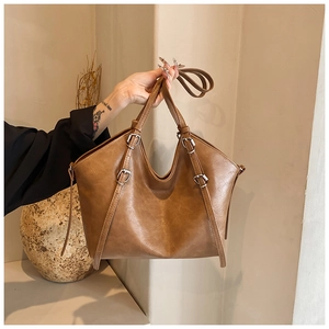 Detail of vintage brown PU leather tote bag with silver hardware and smooth texture