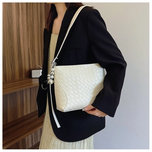 Detail of cream PU woven shoulder bag with metal pearl charm on a stylish commuter model
