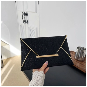Détail d'une pochette enveloppe noire pailletée avec bordure dorée et fermoir métallique