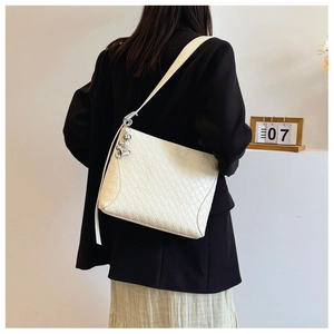 Detail of white woven PU leather shoulder bag with silver heart and pearl charm accessory