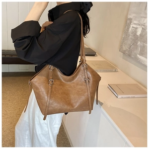 Side view of a vintage brown tote bag featuring textured leather and adjustable buckles