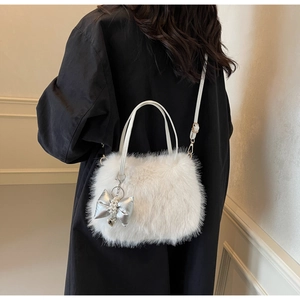 Detail of white plush shoulder bag with silver bow charm and elegant pearl accents