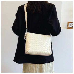 Detail of woven cream PU leather crossbody bag with pearl and metal ball charm on model
