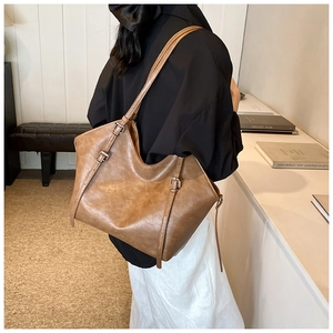 Close-up of brown PU leather tote bag with vintage texture and adjustable metal buckles