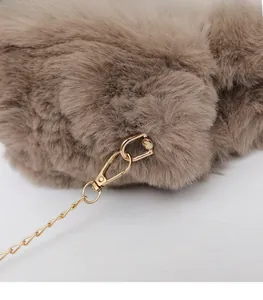 Close-up of golden metal buckle and chain on camel plush faux fur crossbody bag