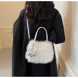 Detail of a white fluffy faux fur crossbody bag with pearl bow charm and silver heart