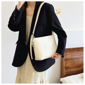 Detail of beige woven PU leather shoulder bag featuring decorative pearl and metal charms