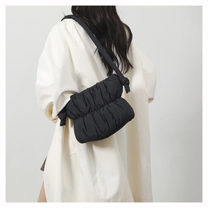 Detail view of black pleated puffer shoulder bag with a knotted strap and quilted texture
