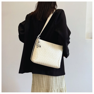 Close-up of white woven PU leather handbag featuring elegant silver heart metal charm