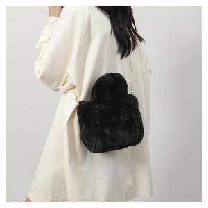 Close-up of black plush crossbody bag with premium gold metal chain strap on model