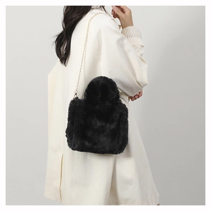 Detail of black faux fur plush crossbody bag featuring an elegant gold metal chain strap