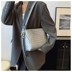 Detail of silver metallic woven PU leather bag with heart charm on a grey suit jacket