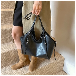Detail of black lychee texture PU leather tote bag with silver metal buckles for women