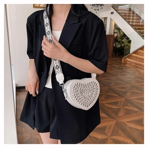 Détail du sac à bandoulière cœur en cuir PU crème avec clous argentés et sangle à motifs