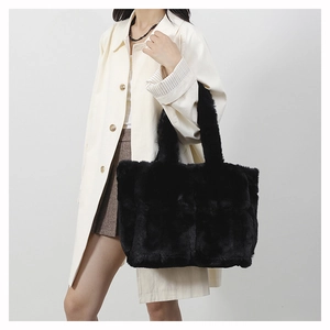 Close-up of black plush tote bag with soft faux fur texture carried by a model