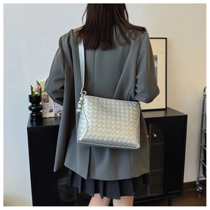 Detail of silver woven PU leather shoulder bag with heart pearl charm on a model