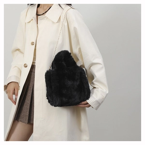Detail of soft black plush shoulder bag with elegant gold metal chain strap on model