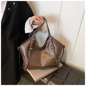 Close-up of brown PU leather tote bag featuring adjustable silver buckle shoulder straps