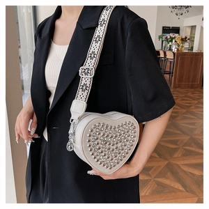 Détail du sac en PU crème en forme de cœur avec rivets argentés et bandoulière