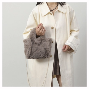 Detail of plush faux fur shoulder bag in khaki with a slender gold chain strap for women