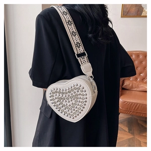 Détail d'un sac bandoulière blanc en forme de cœur orné de strass avec sangle large