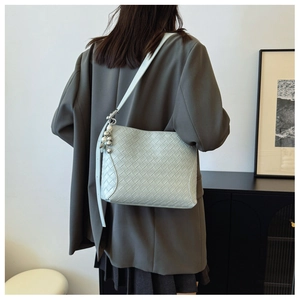 Detail view of woven leather texture and elegant pearl metal charm on light blue shoulder bag