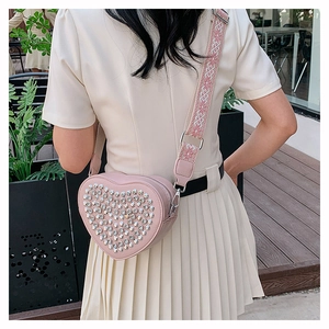 Détail du sac bandoulière rose en forme de cœur en cuir PU avec clous argentés et broderie
