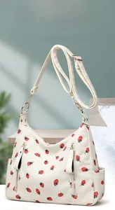 Detailed close-up of corduroy fabric texture and red strawberry prints on the beige bag
