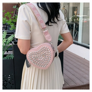 Détail du sac cœur rose en similicuir avec clous argentés et large bandoulière jacquard
