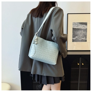 Detail of light blue woven PU leather shoulder bag with pearl heart charm on model