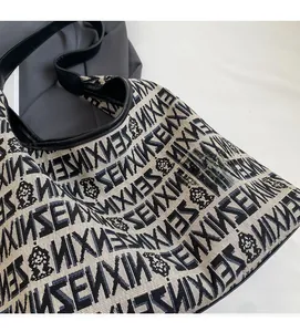Close-up of knit tote bag showing jacquard fabric with monkey pattern and leather trim