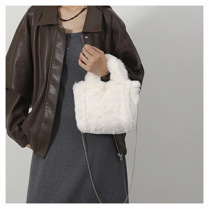 Close-up of white plush crossbody bag with delicate gold chain strap on model clothing