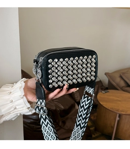 Detail of black PU camera bag with silver rhinestones and geometric woven shoulder strap