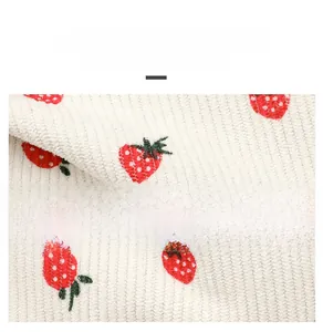 Detail of white knitted fabric with embroidered red strawberries for a summer shoulder bag