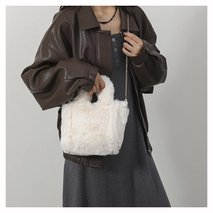 Detail of white faux fur shoulder bag with soft plush texture and golden chain strap