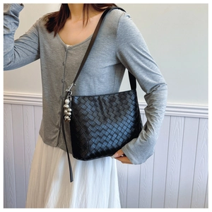 Detail of black PU leather woven shoulder bag featuring silver metal ball ornament