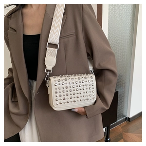 Detail view of cream PU leather crossbody bag with silver studs and wide patterned strap