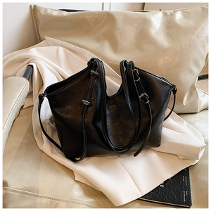 Minimalist black PU leather shoulder bag with silver buckles on white blazer background