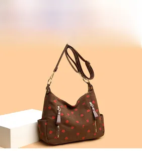 Detail of vintage corduroy shoulder bag featuring red strawberry print and leather strap