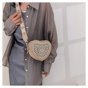 Détail du sac à bandoulière en forme de cœur avec strass argentés et sangle jacquard