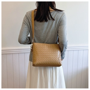 Detail of light brown woven PU leather shoulder bag with decorative bead strap charm